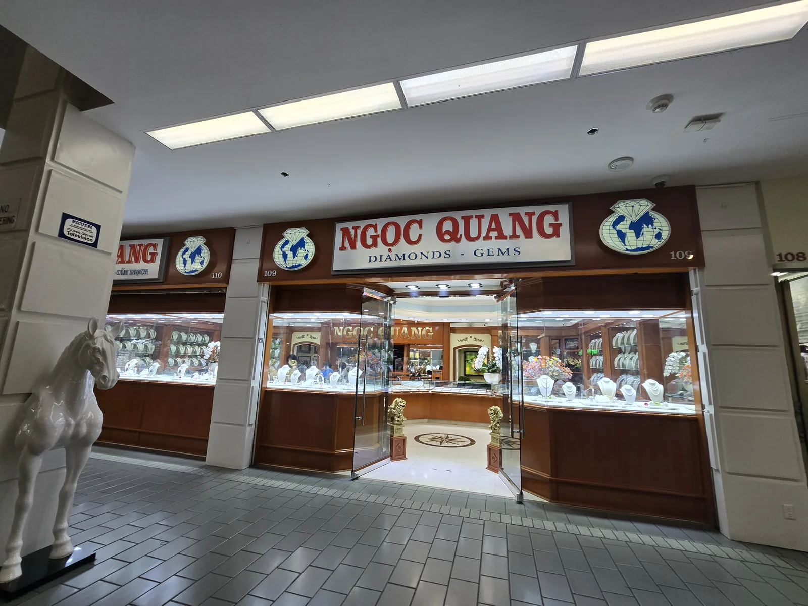 Ngoc Quang Diamonds & Gems 门面,深色木饰柜台,门口白马雕塑