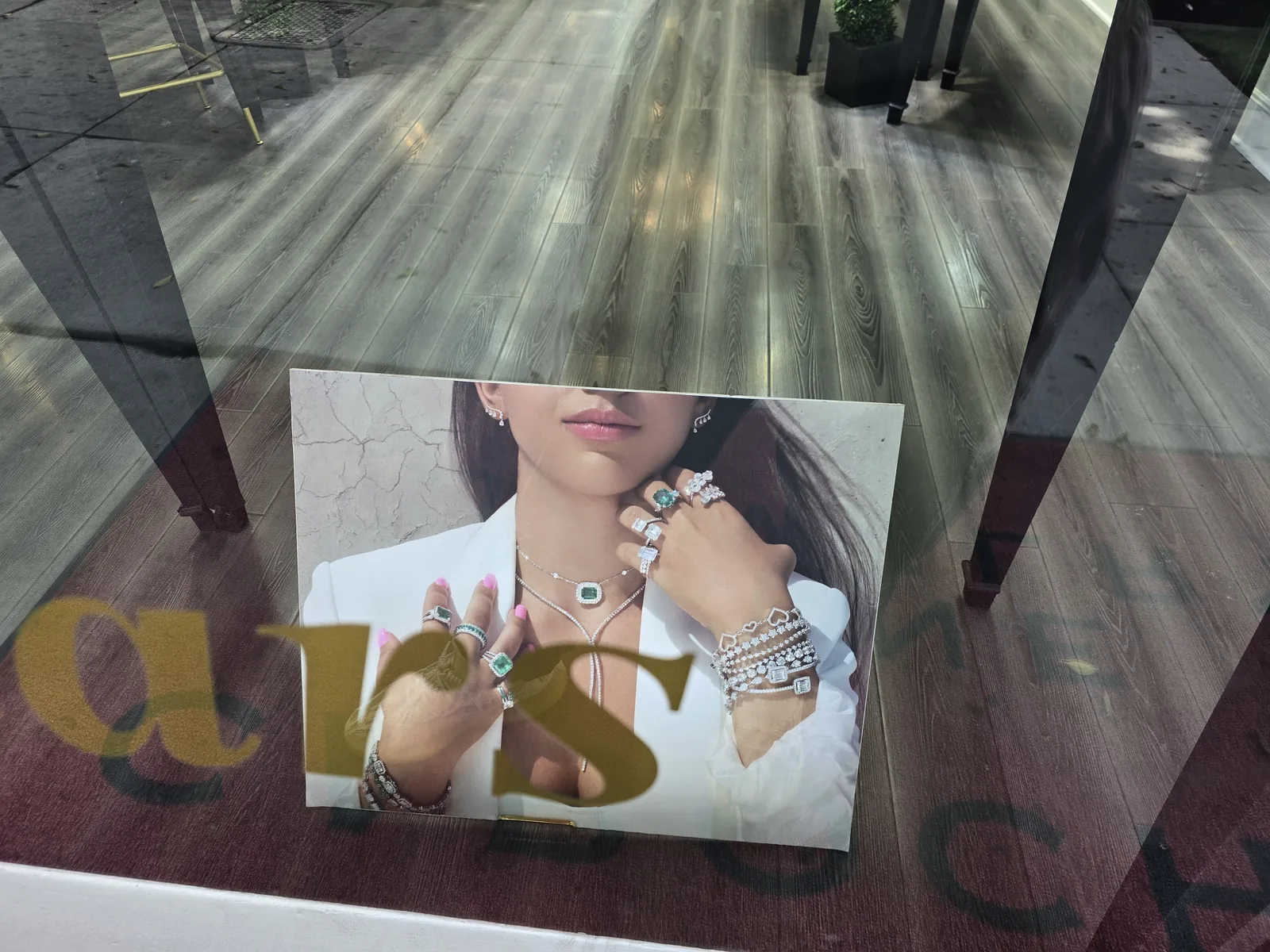 Cabochon 橱窗里的模特海报,白衬衫模特佩戴祖母绿与钻石戒指、多条网球手链