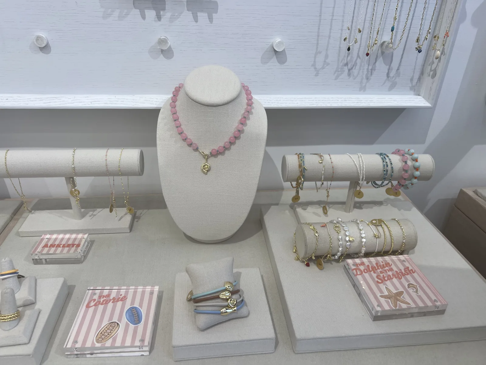 gorjana 陈列桌,粉色串珠项链、彩石手链、The Coterie 与 Anklets 粉白条纹小牌