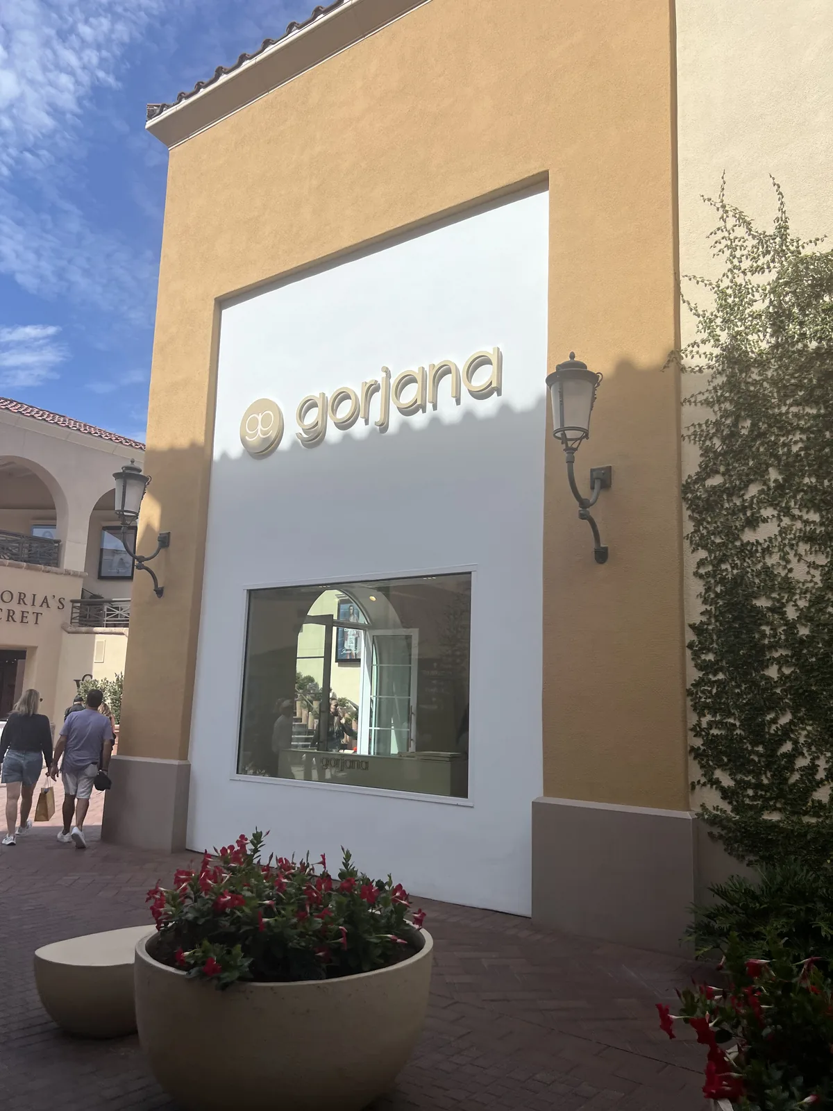 gorjana 门店在 Fashion Island 露天商场的外景,地中海建筑、爬藤与花坛,旁边是 Victoria's Secret