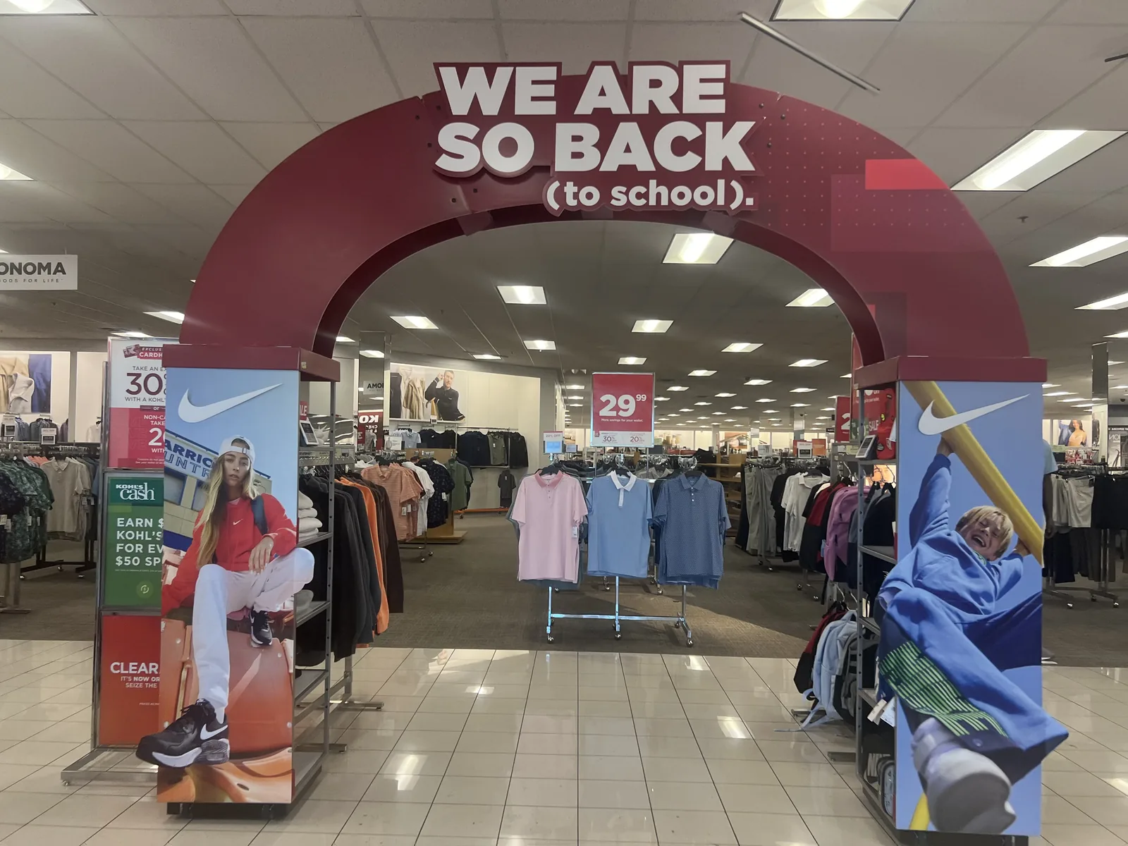 Kohl's 返校季红色拱门 WE ARE SO BACK to school,两侧 Nike 广告柱与 29.99 美元 T 恤堆头