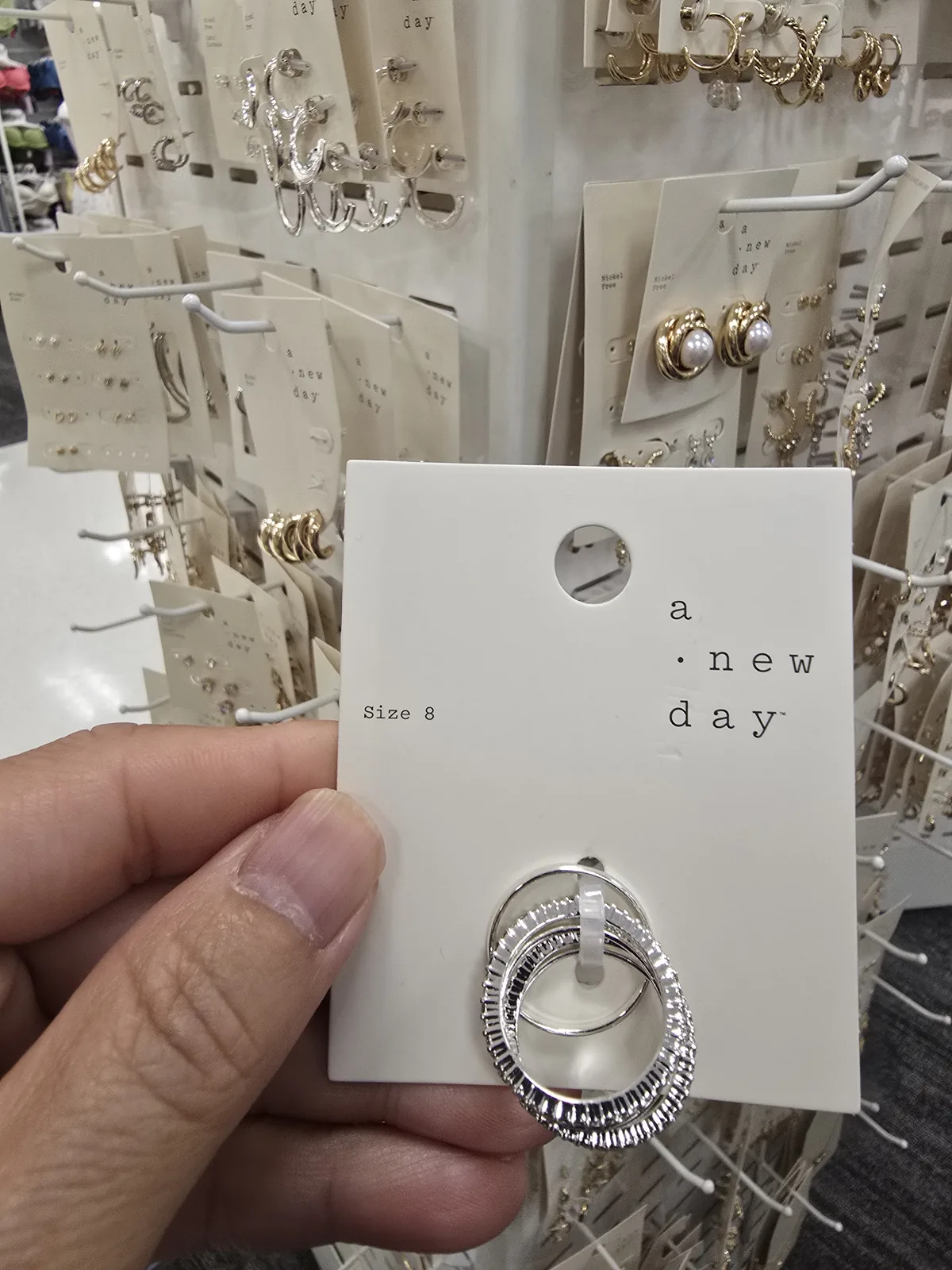 Target 店内珠宝配饰区,多座白色挂板塔陈列纸卡装饰品,远处女装区